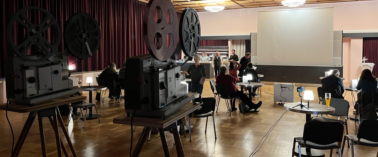 Kino alte Strumpffabrik Personen versammeln sich in einem Raum um an einer Projektionsleinwand Präsentation zu sehen, die mit alten Kinoprojektoren gezeigt wird.
