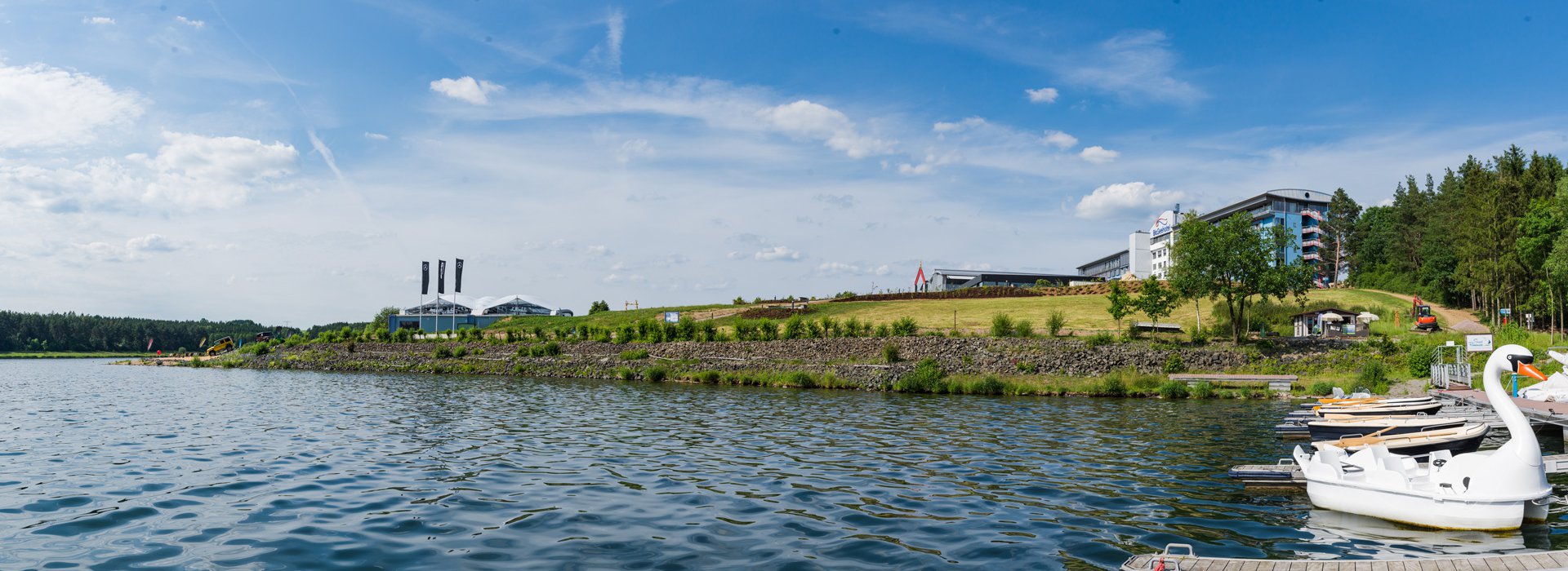 SRE bloggt Blick vom Steg in Richtung Bio-Seehotel Zeulenroda mit einer großen Wasserfläche im Vordergrund