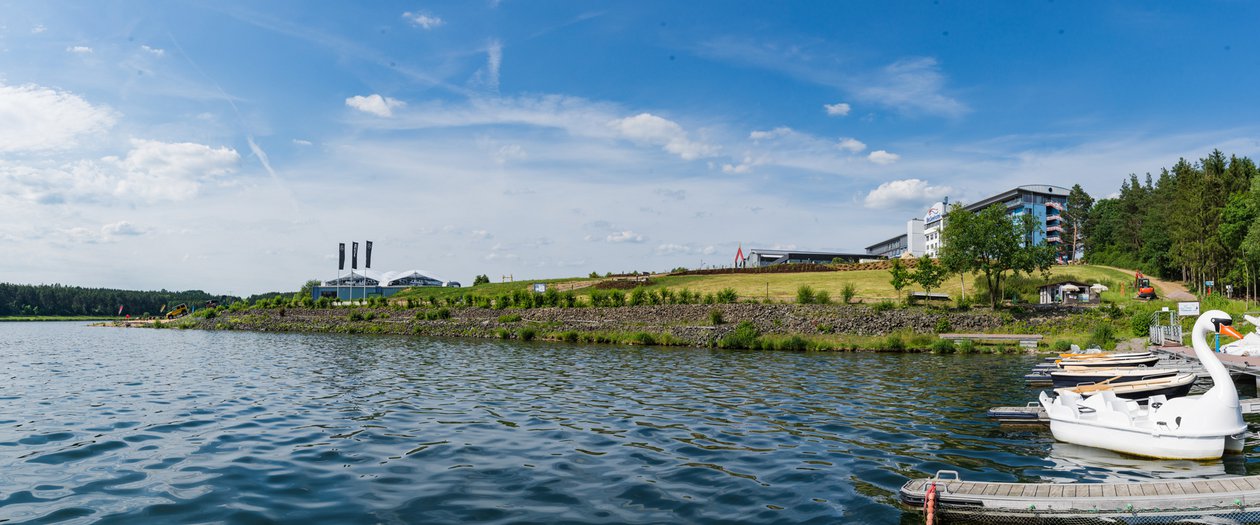 Blick vom Steg in Richtung Bio-Seehotel Zeulenroda mit einer großen Wasserfläche im Vordergrund