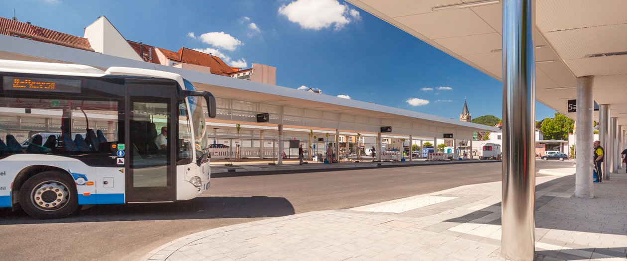 Ein weiß-blauer Bus steht an einem modernen Busbahnhof