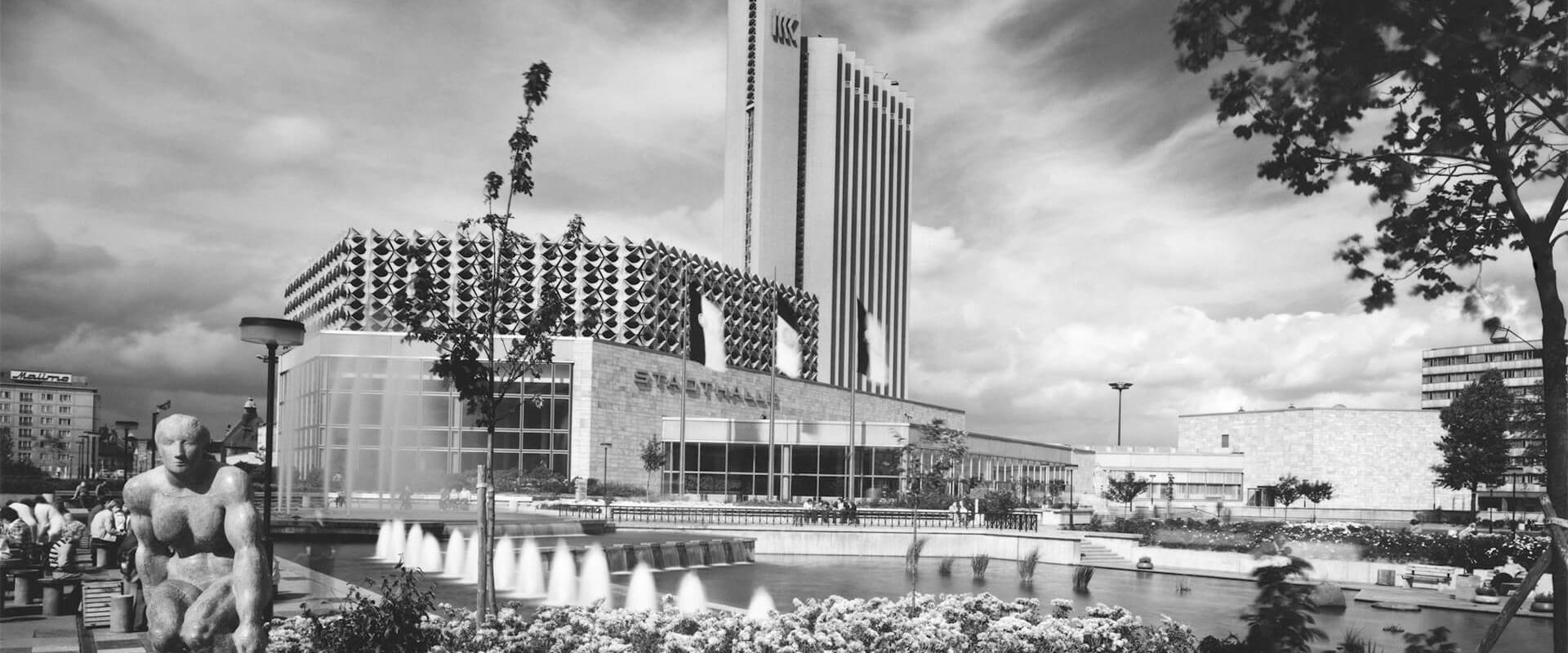 Schwarz-weiß-Foto eines Brunnens vor einem Gebäude, das eine ruhige und elegante Atmosphäre vermittelt.