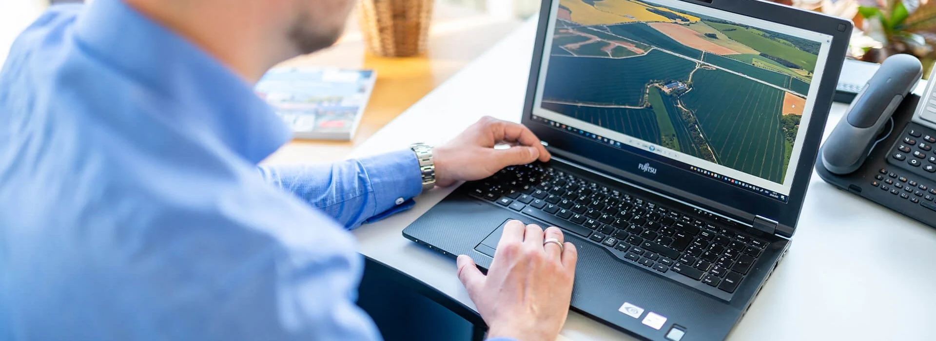 Bildbeschreibung / description: Ein Mann arbeitet am Laptop und betrachtet landwirtschaftliche Informationen auf einer Farm.