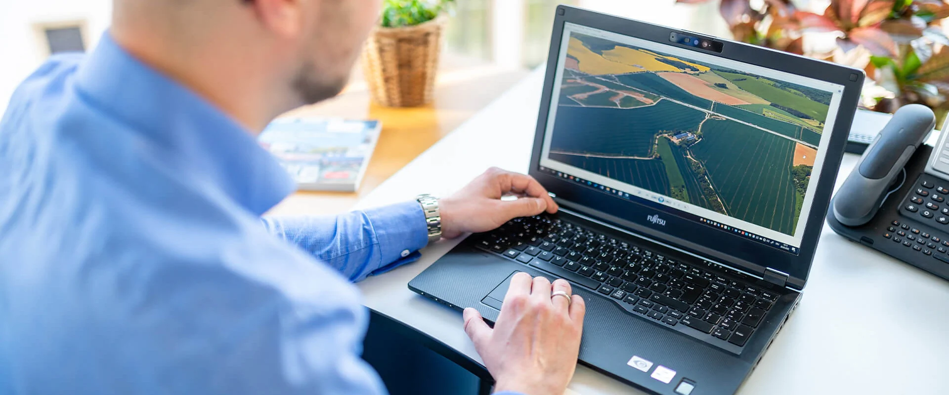 Bildbeschreibung / description: Ein Mann arbeitet am Laptop und betrachtet landwirtschaftliche Informationen auf einer Farm.