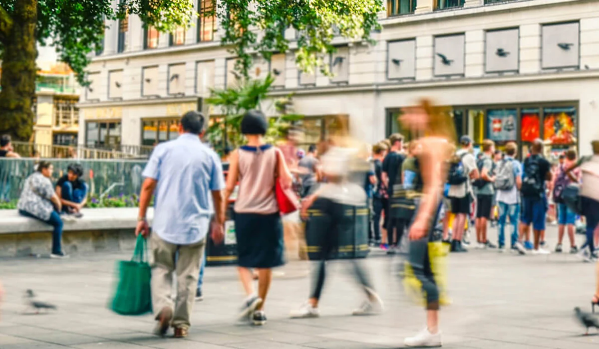 Bildbeschreibung / description: Zeitrafferbild bei dem Menschen durch einen Stadtplatz gehen, umgeben von beeindruckenden Gebäuden im Hintergrund.