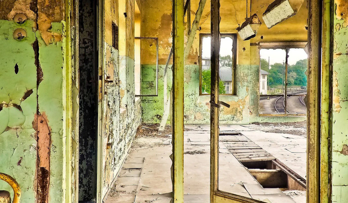 Bildbeschreibung / description: Verfallener Bahnhof mit beschädigten Fenstern und buntem Graffiti, das die Geschichte des Ortes erzählt.