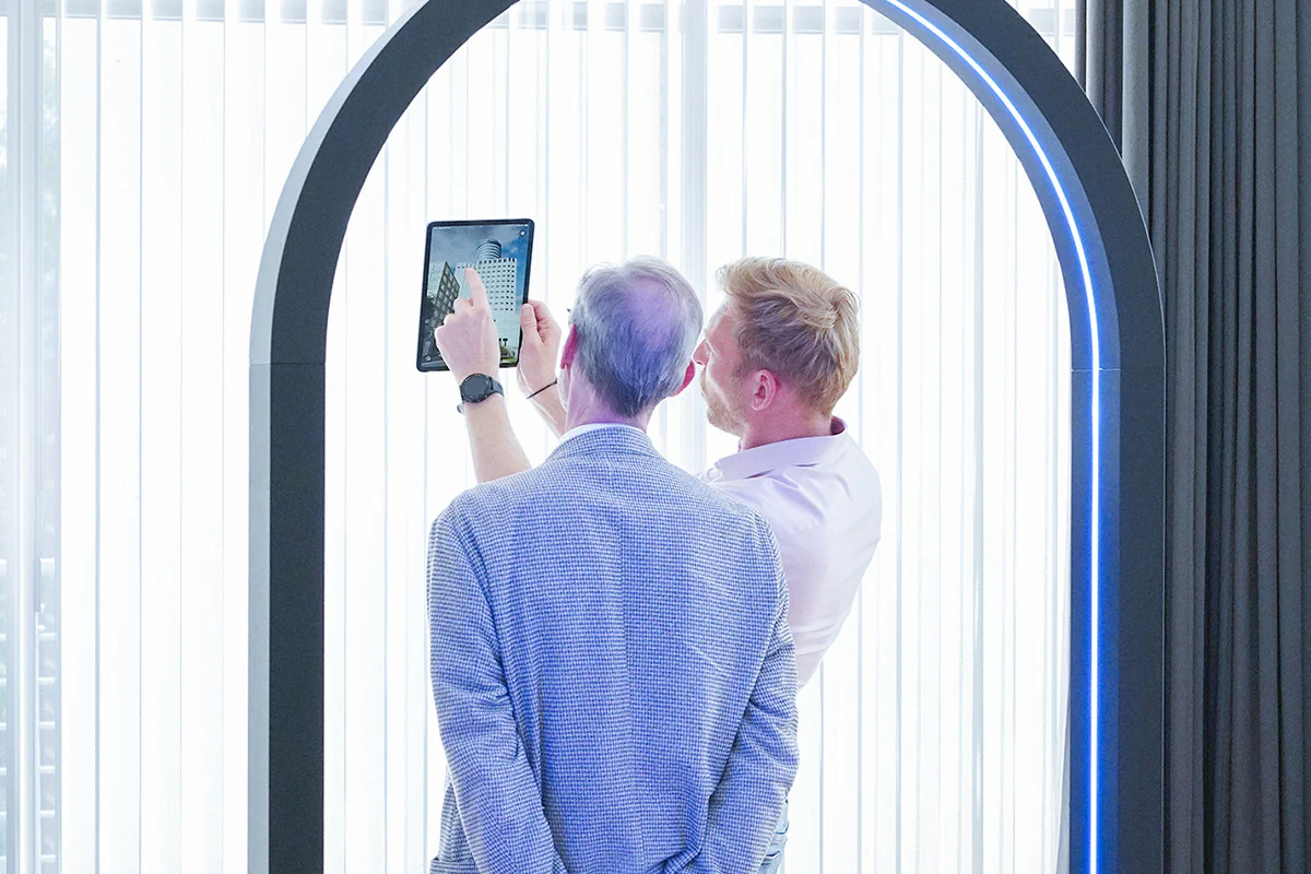 Bildbeschreibung / description: Zwei Männer schauen auf ein Tablet, während sie unter einem Bogen stehen.