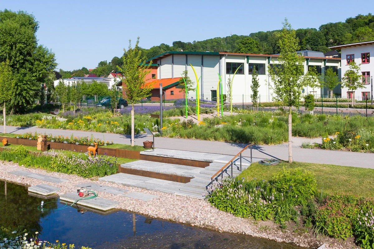 Stadtumbau Bildbeschreibung / description: Ein Fluss, der durch einen Park fließt, umgeben von Bäumen und Grünflächen, ideal für Erholung und Naturgenuss.