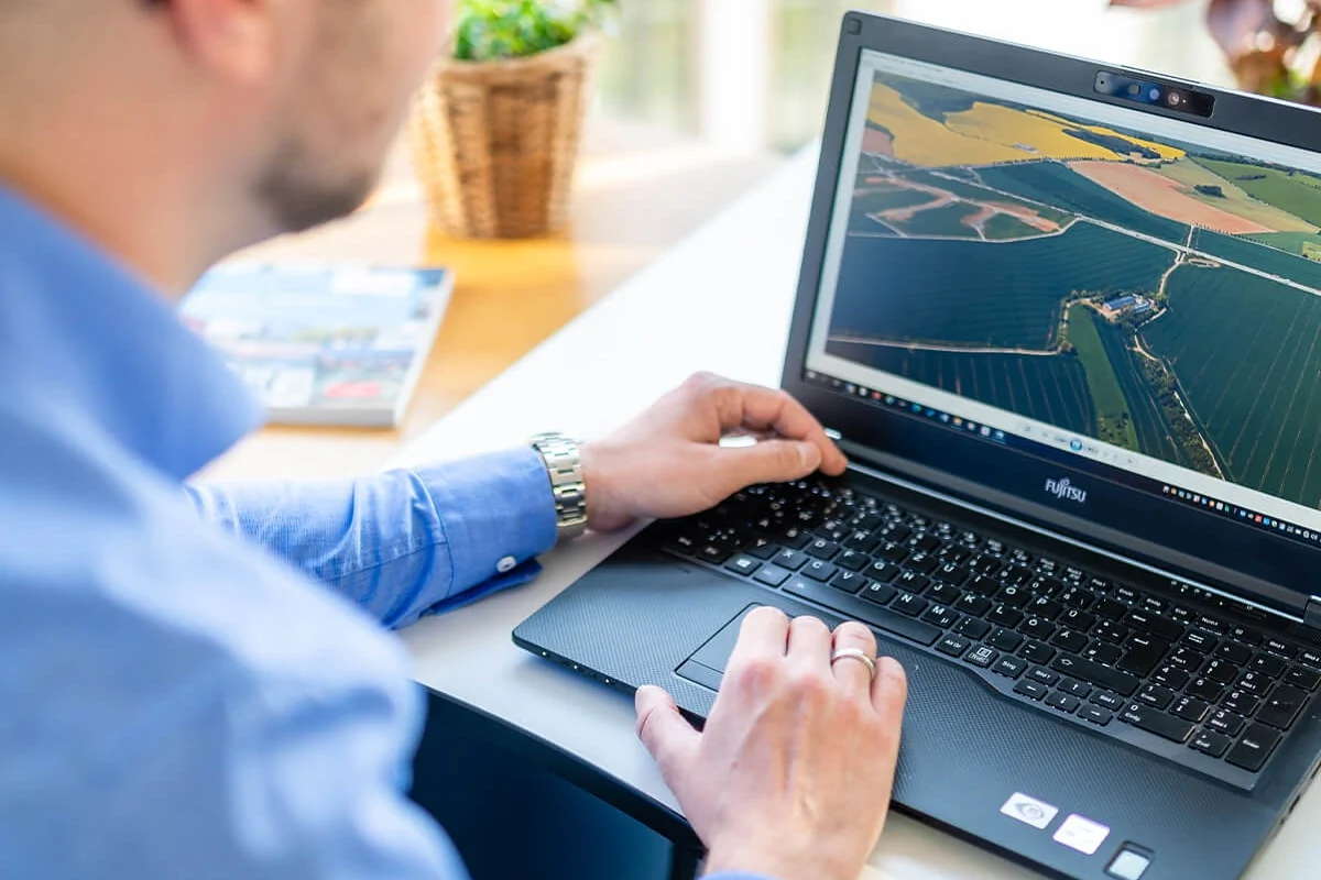 Bildbeschreibung / description: Ein Mann arbeitet am Laptop und betrachtet landwirtschaftliche Informationen auf einer Farm.