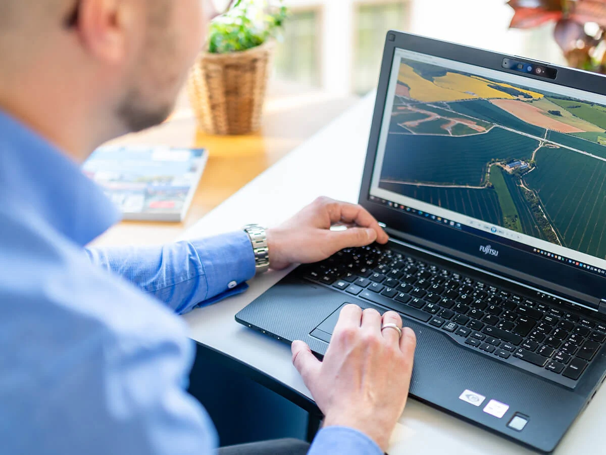 Bildbeschreibung / description: Ein Mann arbeitet am Laptop und betrachtet landwirtschaftliche Informationen auf einer Farm.